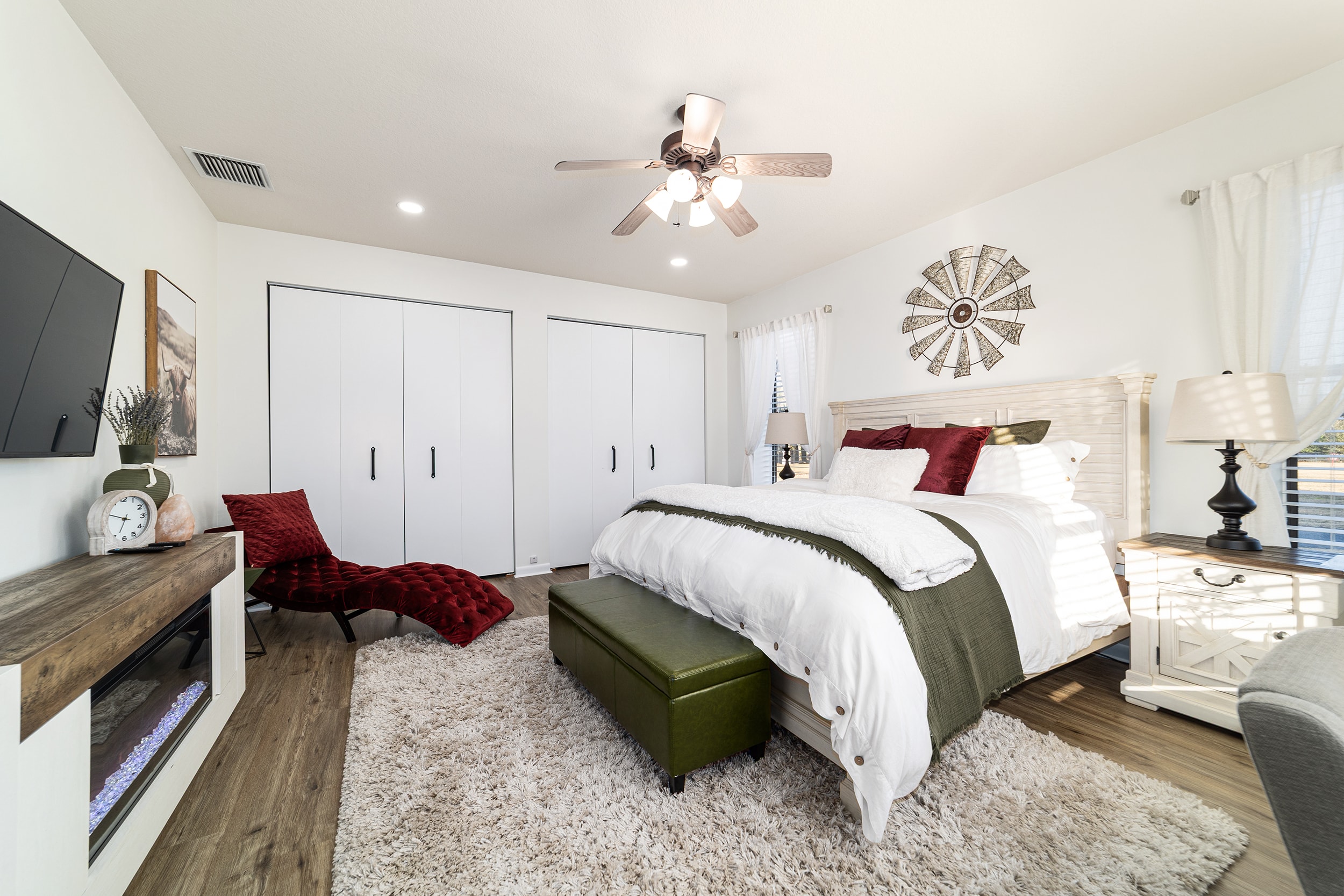 Bright bedroom with king bed, red accent pillows, and farmhouse decor