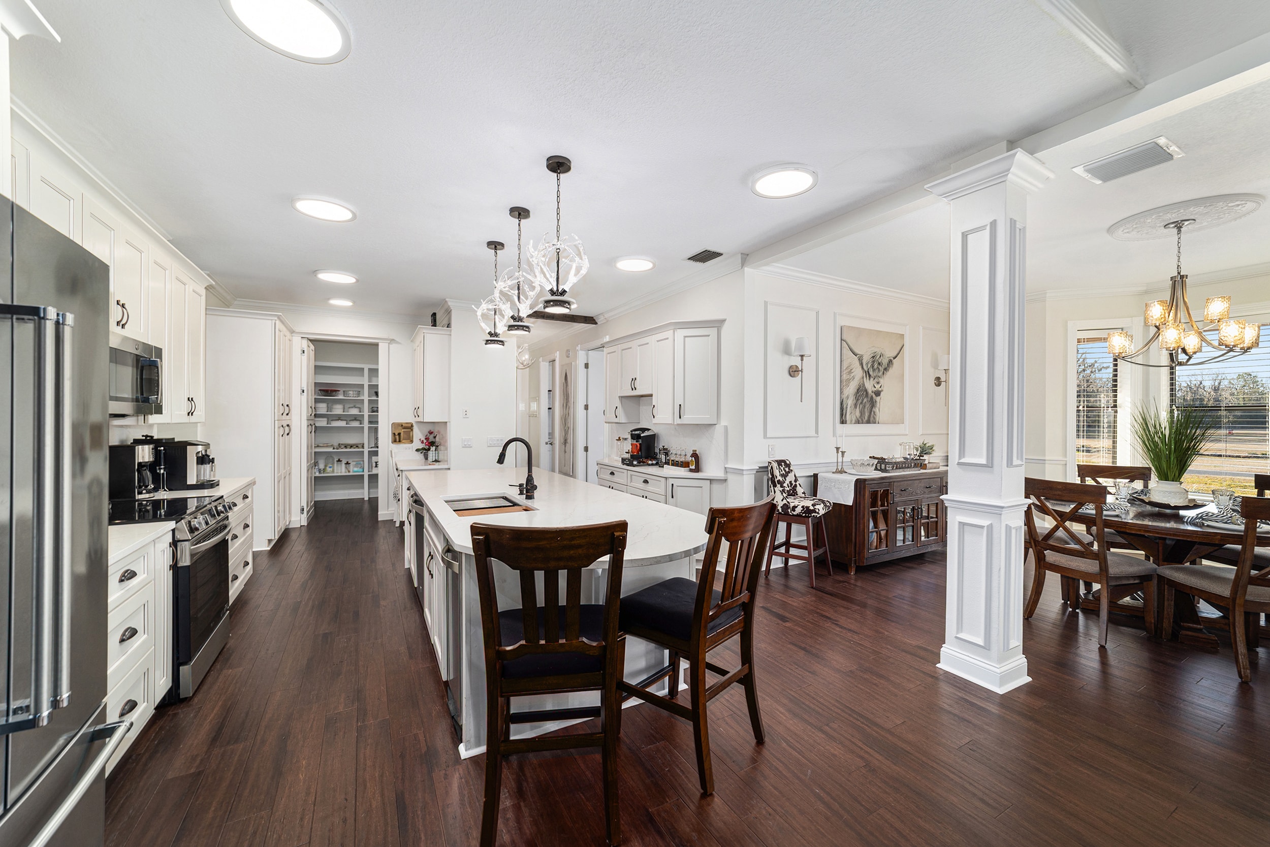 Grand chef's kitchen with large island, white cabinetry, and antler chandelier