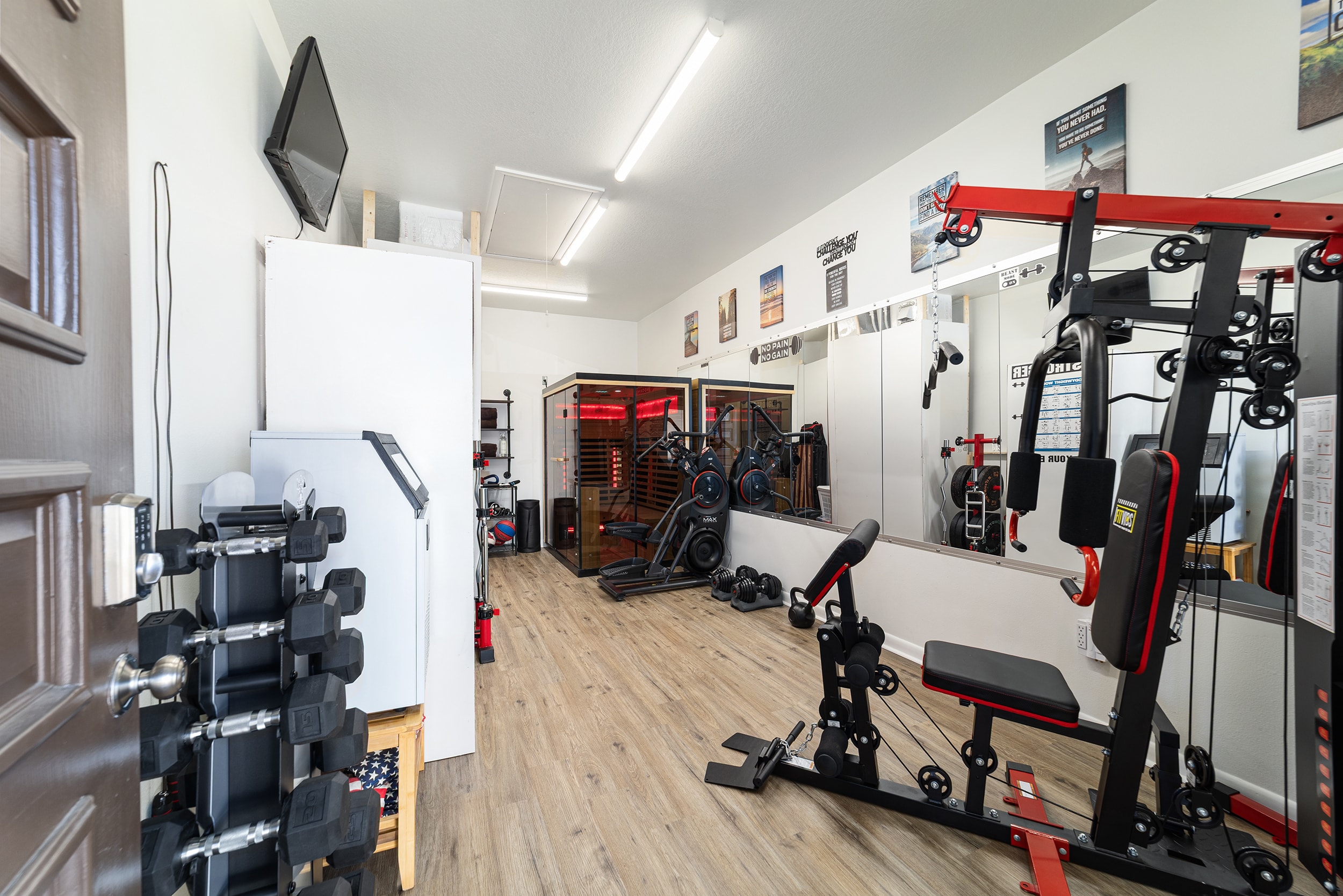 Fully equipped home gym with weights, cable machine, and infrared sauna