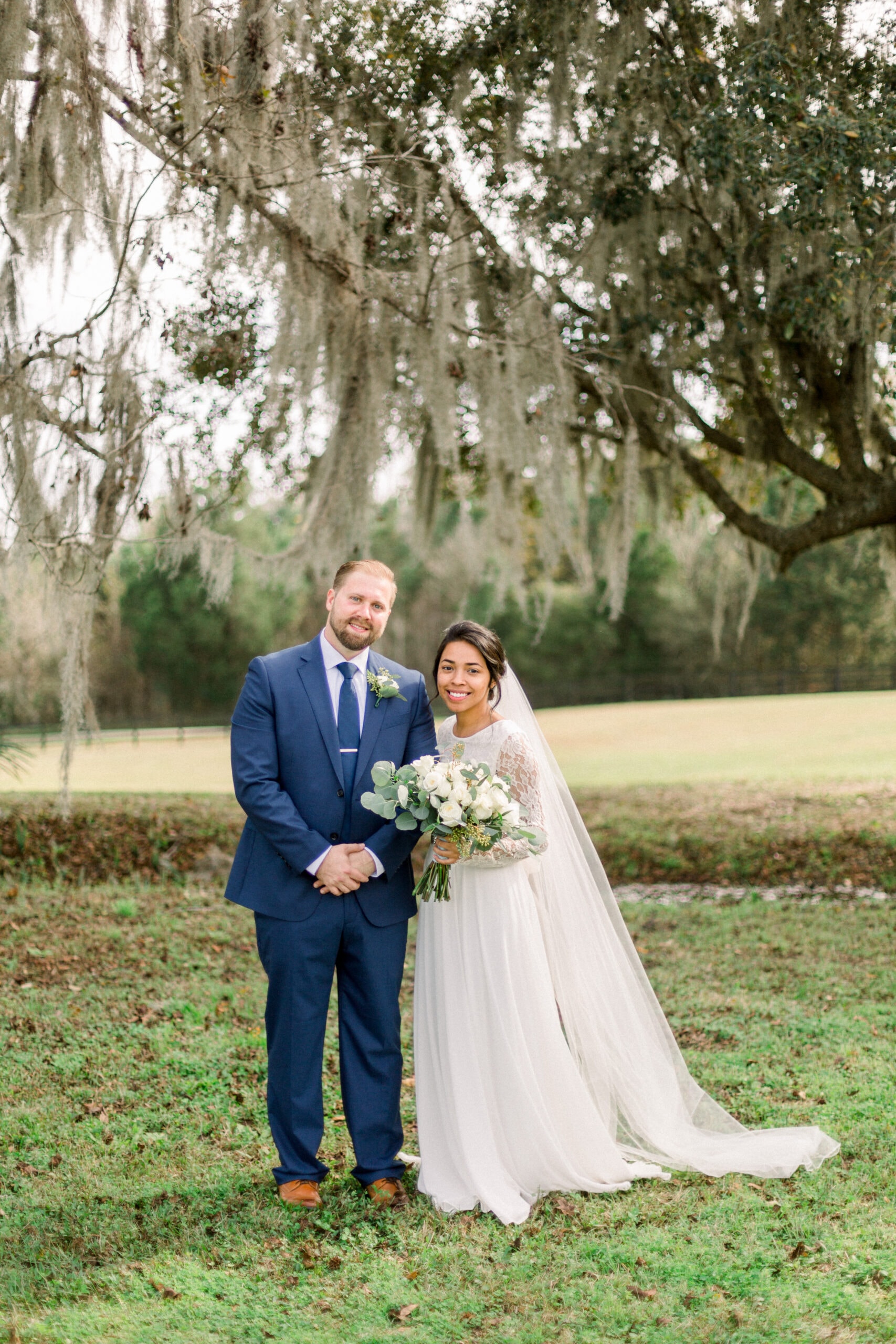Bride and groom portrait under sweeping Spanish moss oak trees on the ranch grounds