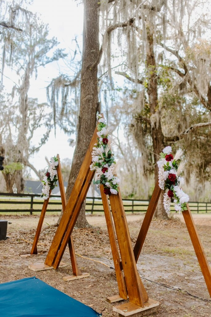 Bride and groom sharing their first kiss with confetti falling under the floral arch