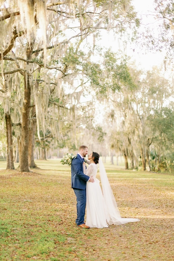 Romantic bride and groom portrait with flowing veil under Spanish moss oaks